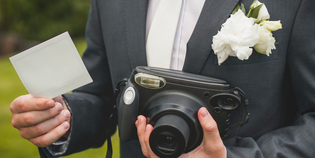 part-of-groom-with-retro-camera-and-empty-card